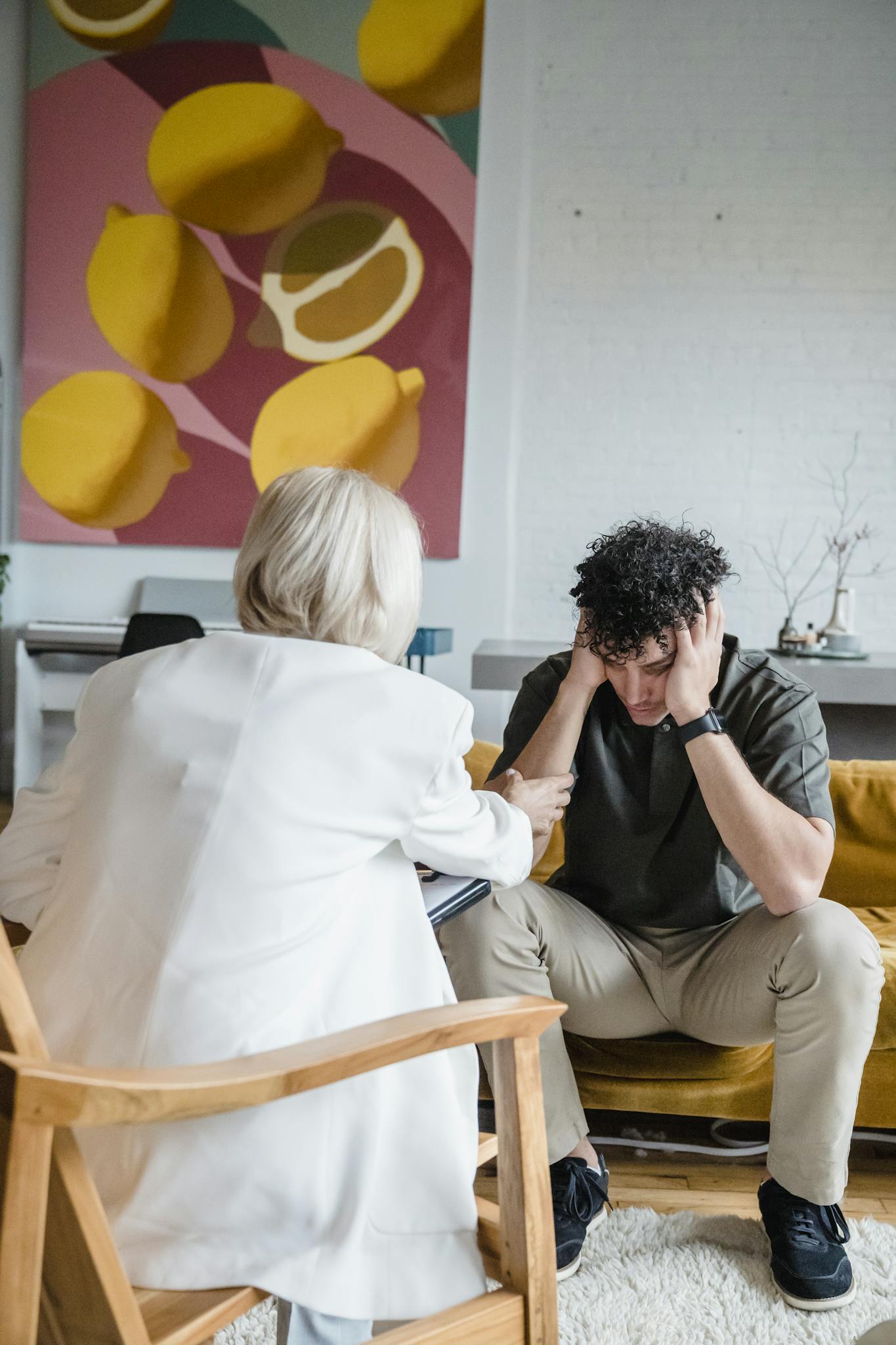 Therapist engages with a young man during a counseling session in a modern office setting.